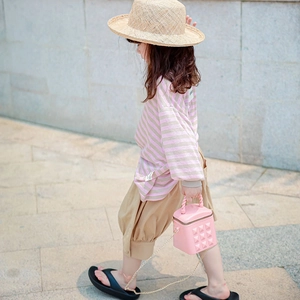Pink quilted crossbody bag for girls with gold studs and a woven handle outdoors