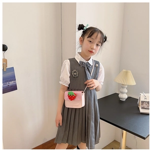 Detailed embroidery of a black school emblem on the chest of a gray girl's pinafore dress