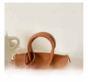 Détail macro du mini sac en cuir marron avec fermoir doré et accessoire étoile