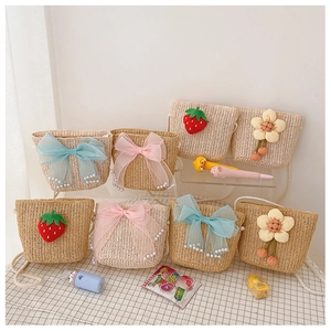 Detail of assorted girls' straw crossbody bags with cute strawberry and flower charms