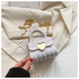Detail der weißen Herz-Verschlusskappe und Goldkette an der gesteppten Mini-Tasche