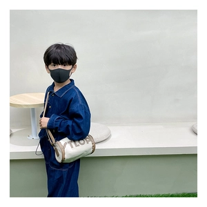 Détail d'un sac cylindrique blanc avec lettres TLOA pour tenues de mode enfantine