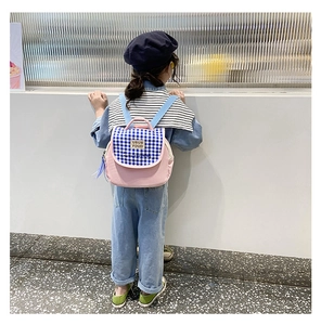 Dettaglio di un bambino con uno zaino in tela a scacchi rosa e blu sul retro