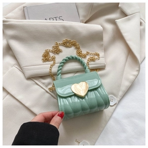 Detail der mintgrünen Jelly-Tasche mit Herzverschluss, gedrehtem Griff und Goldkette