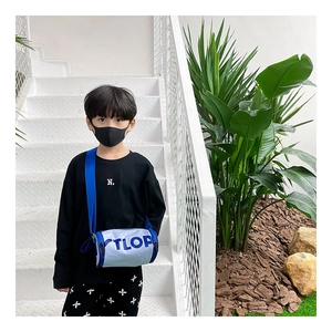 Détail du sac bandoulière cylindrique bleu et blanc avec lettrage TLOP enfant
