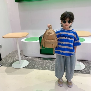 Cute khaki lightweight backpack for kids shown by child model in indoor setting
