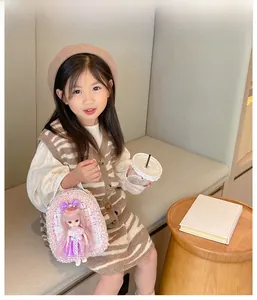 Girl's pearl lace doll handbag shown with a young model in a warm indoor setting