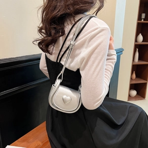 Mini sac selle argenté avec cœur et fine bandoulière porté par un mannequin de style
