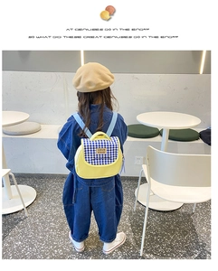 Dettaglio dello zaino giallo per bambini con patta a quadretti blu e cinghie