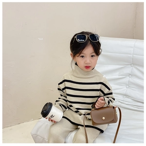 Detail of child wearing a striped knit two-piece sweater and trousers set in beige