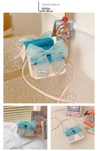 Detail of child's mini crossbody bag with blue sequin fabric and large tulle bow with pearls