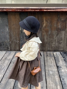 Détail d'un petit sac bandoulière en cuir vintage avec une tenue rétro pour enfants