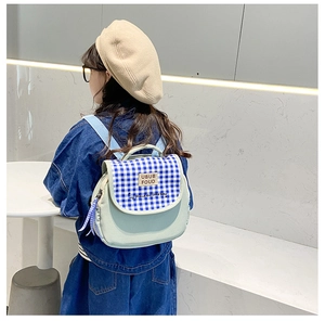 Dettaglio dello zaino per bambini in tela verde con patta a scacchi blu e ricami