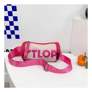 Détail d'un sac bandoulière cylindrique rose et beige avec lettrage TLOP pour enfants