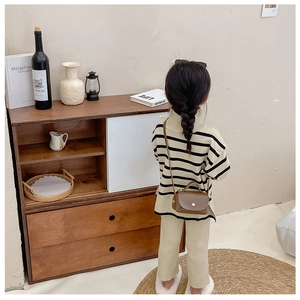Rear view of a girl wearing a brown leather crossbody mini bag with a striped sweater