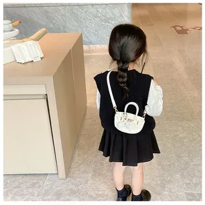 Vue arrière d'un enfant portant un mini sac bandoulière blanc en similicuir à boucle dorée