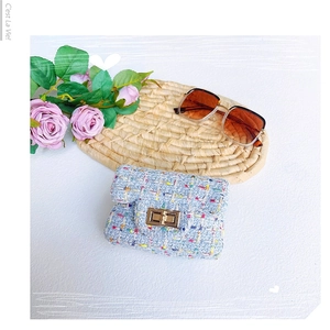 Blaue Tweed-Mini-Umhängetasche mit goldener Schnalle und Accessoires auf Strohmatte