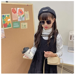 Detailed view of child fashion outfit featuring a mini beige leather crossbody bag