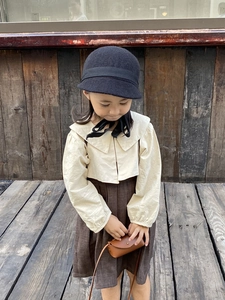 Détail d'un ensemble mode enfant avec chapeau en laine, chemisier blanc et sac bandoulière
