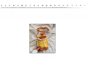 Detail of handmade knitted duck crossbody bag with measuring scale for size reference