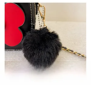 Détail du pompon en fausse fourrure noire et du fermoir mousqueton doré sur un sac chic