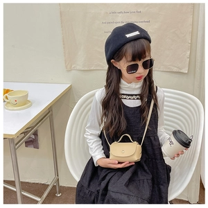 Mini beige children's crossbody bag with semi-circular flap shown in a lifestyle setting