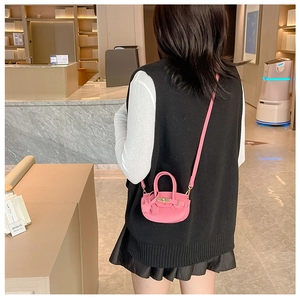Mini sac bandoulière rose en similicuir porté par un mannequin dans un cadre moderne