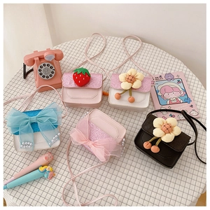 Flat lay detail of colorful PU leather crossbody bags with strawberry and bow decorations