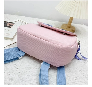 Dettaglio dello zaino in tela rosa con spallacci blu e bordo a quadretti per bambini