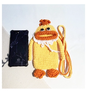 Detail of hand-knitted yellow duck crossbody bag showing texture and size with a phone
