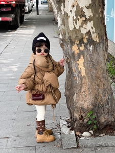 Détail d'un mini sac bandoulière marron roux porté avec une doudoune marron pour enfant