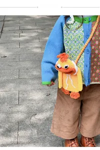 Detail of a handmade yellow crochet duck crossbody bag worn with a colorful cardigan
