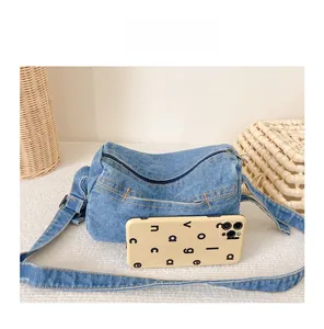 Blue denim kids shoulder bag size comparison with a smartphone in a lifestyle setup