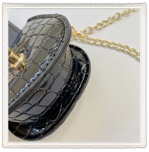 Detail of mini black crocodile embossed bag featuring a golden chain and metal twist lock