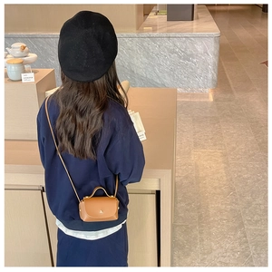 Mini brown leather crossbody bag for girls shown on a model in a boutique setting