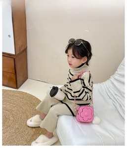 Fille en tricot rayé et pantalon beige avec un petit sac bandoulière fleur rose