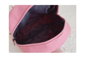 Detail shot of mini pink canvas backpack interior featuring dark lining and multi-pockets