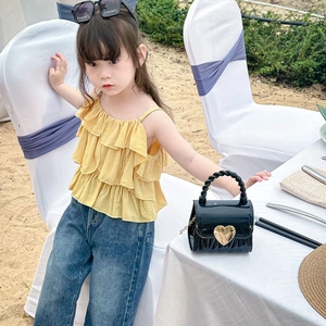 Modisches gelbes Stufenoberteil mit Jeans und Herz-Mini-Tasche für kleine Mädchen