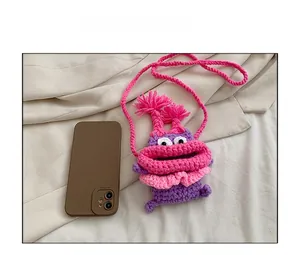 Comparaison de taille du sac bandoulière monstre en tricot violet et rose avec un smartphone