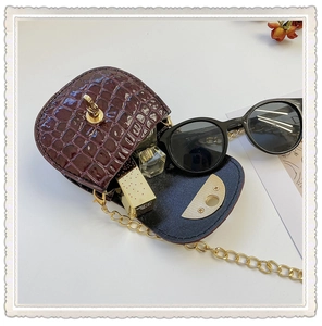 Detail view of mini burgundy crocodile textured saddle bag with gold chain and interior space
