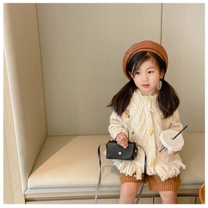 Detailed view of cream cable knit cardigan with delicate floral embroidery and fringe hem