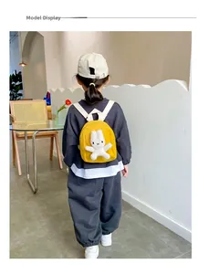 Detail display of a yellow canvas toddler backpack featuring a cute 3D plush rabbit decoration