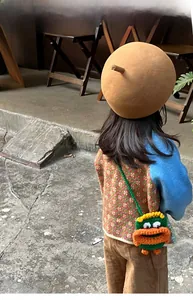Détail d'un sac bandoulière monstre tricoté main pour enfants en vert et orange