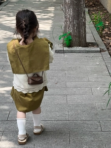 Vue arrière d'un petit sac à bandoulière en cuir marron foncé avec un gilet en dentelle blanche