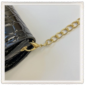 Detail of black crocodile texture bag with gold chain strap and lobster clasp