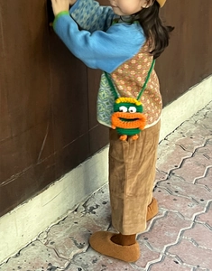 Gros plan d'un enfant portant un sac bandoulière en tricot monstre vert avec bouche orange
