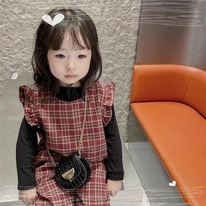Close-up of girls black faux crocodile saddle bag with gold chain and red plaid dress