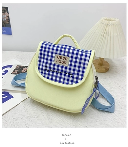 Dettaglio mini zaino in tela con patta a quadretti blu su tessuto jacquard bianco