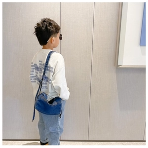 Detail of a navy denim crossbody bag for kids paired with a stylish letter print white shirt