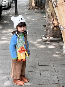 Toddler modeling a handmade duck-shaped crochet crossbody bag with an autumn knit outfit